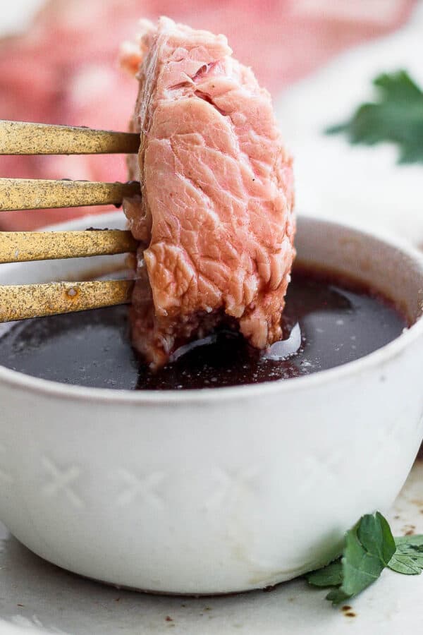 Someone dipping prime rib in au jus.