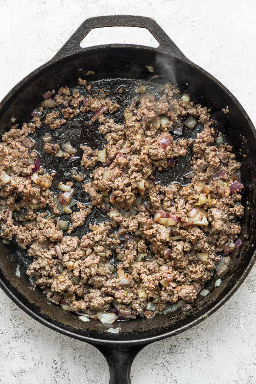 Garlic, onion, and ground beef browned in the pan.