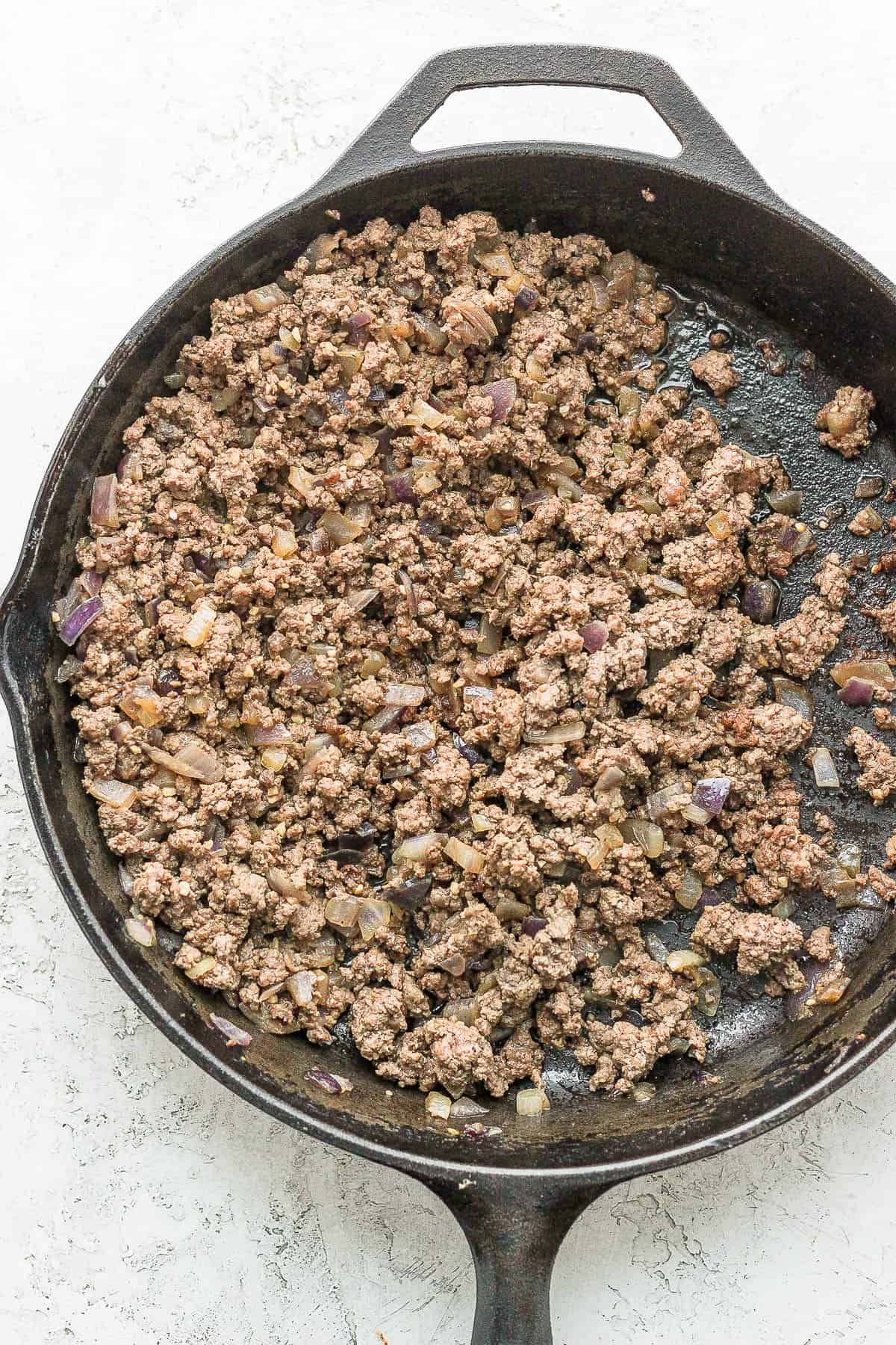 Browned ground beef in a cast iron skillet.