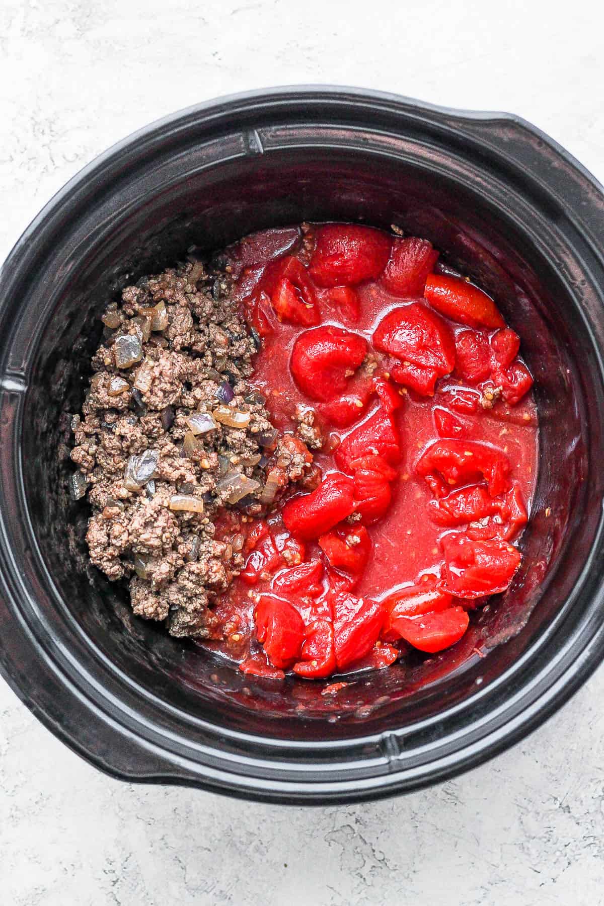 Ground beef and canned tomatoes in a slow cooker.