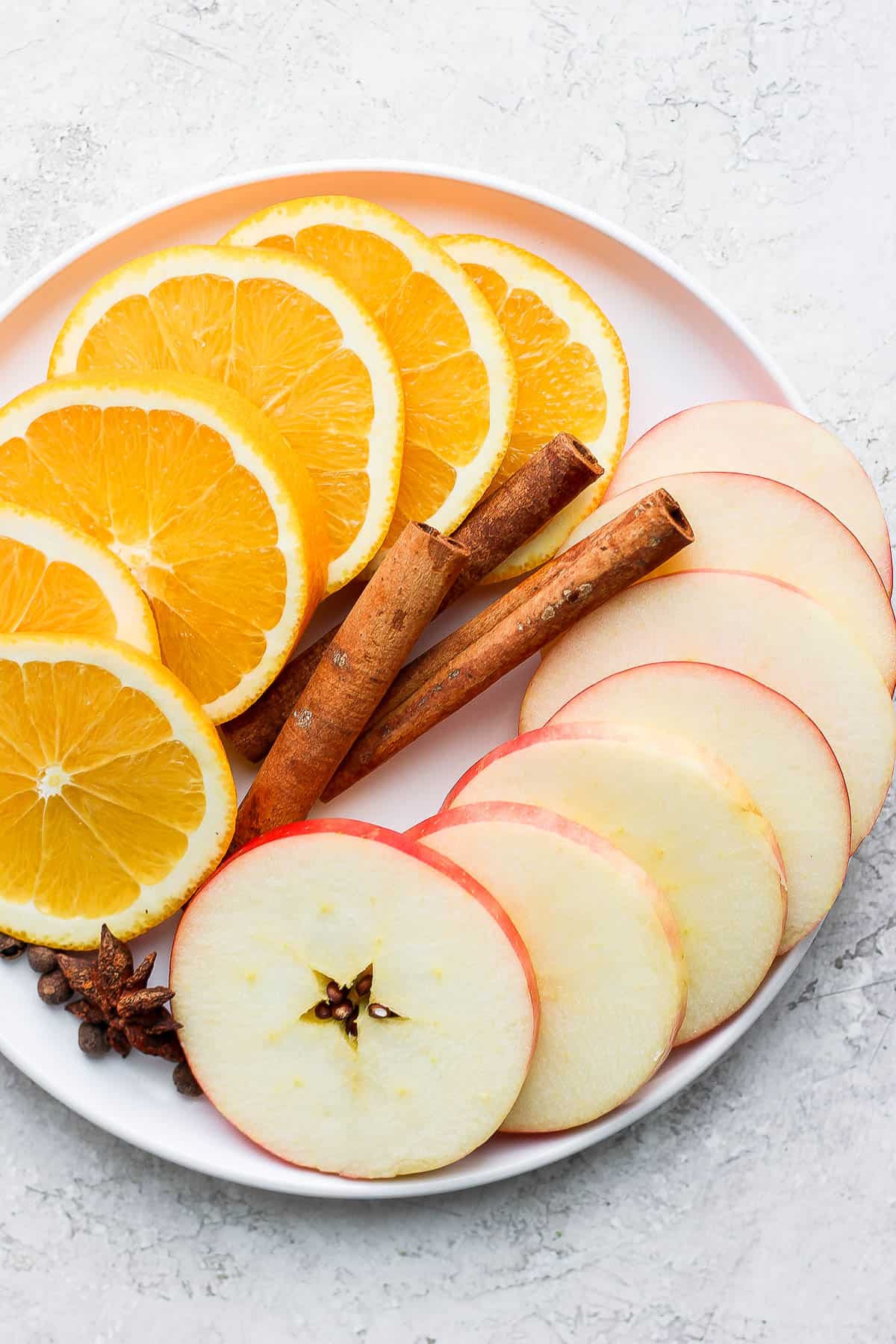 Spices and sliced fruit on a plate.