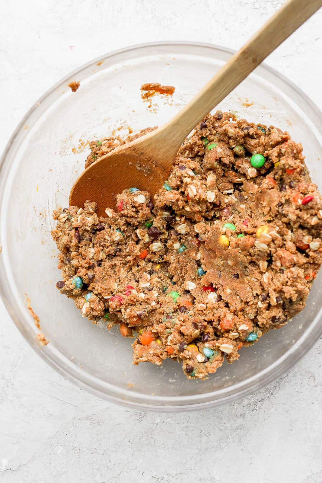 Vegan cookie dough in a mixing bowl with a wooden spoon.