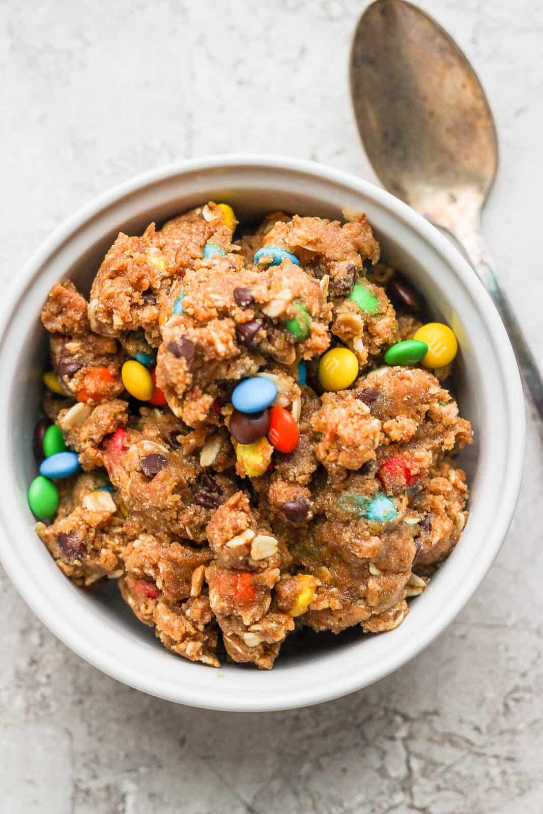 Vegan cookie dough in a bowl with a spoon on the side.