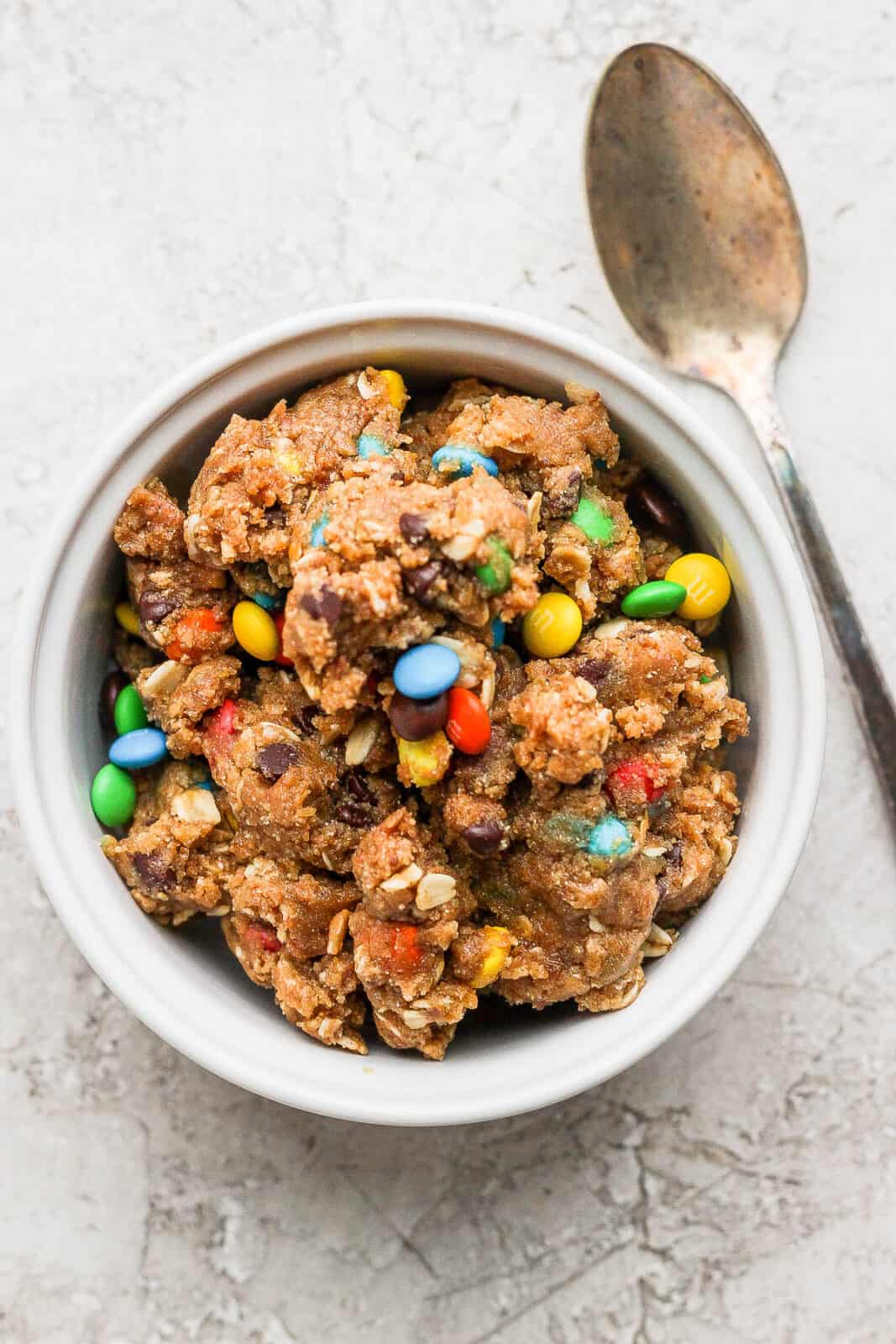 Vegan cookie dough in a bowl with a spoon on the side.