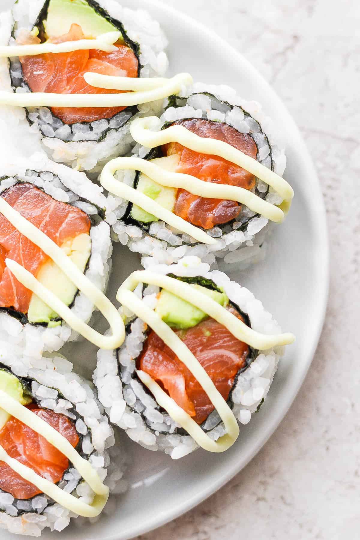 A salmon sushi roll with wasabi mayo on top.