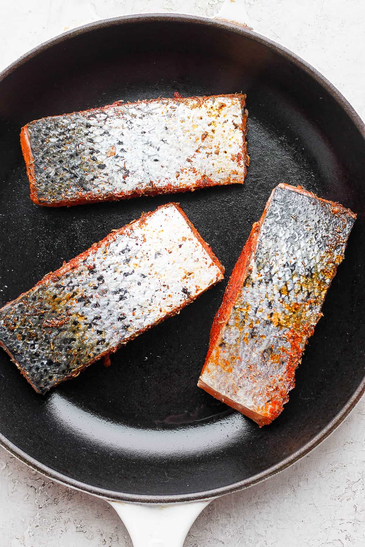 Salmon fillets in cast iron skillet with skin-side up.