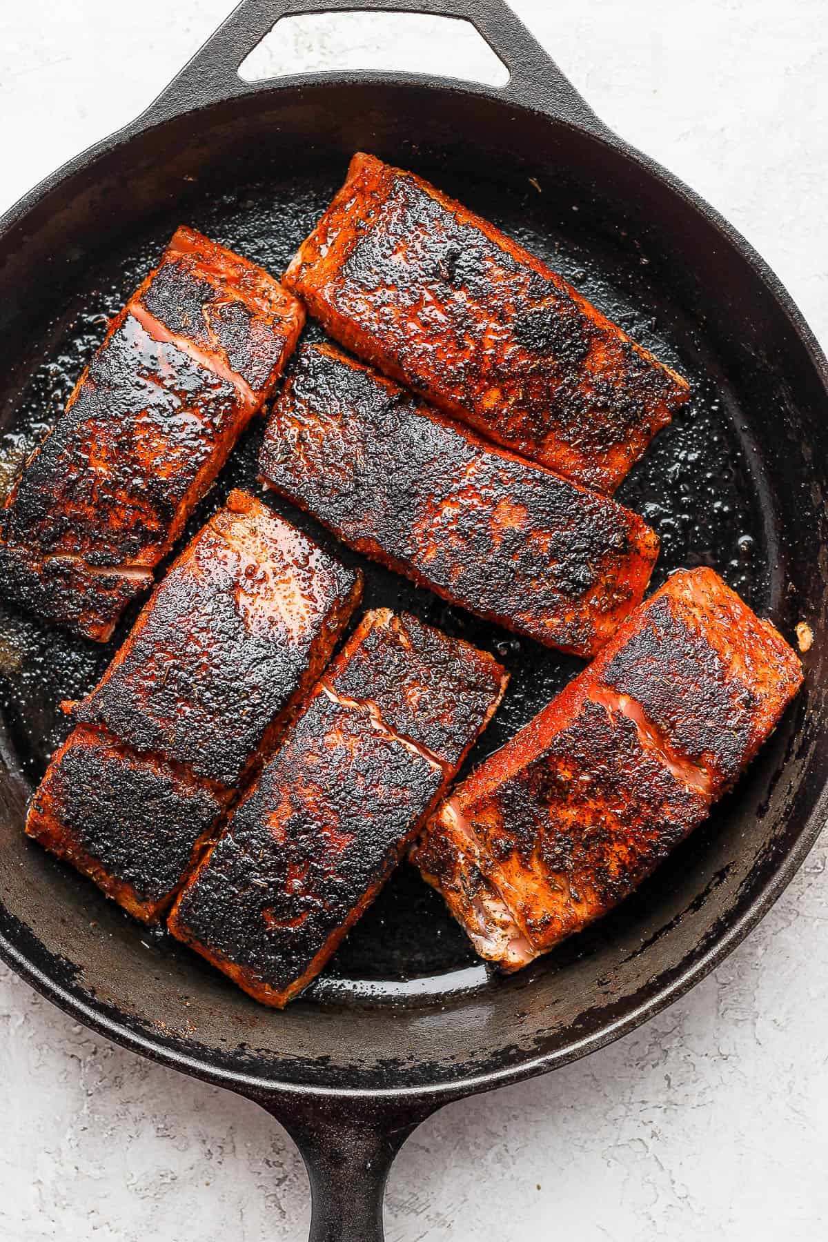 Blackened salmon fillets in a cast iron skillet.
