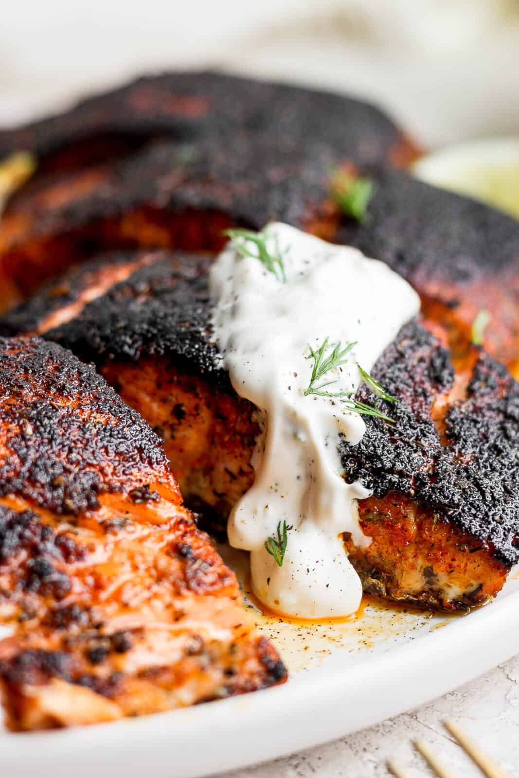 Close-up look at the blackened salmon fillets with a dollop of dill sauce on top.