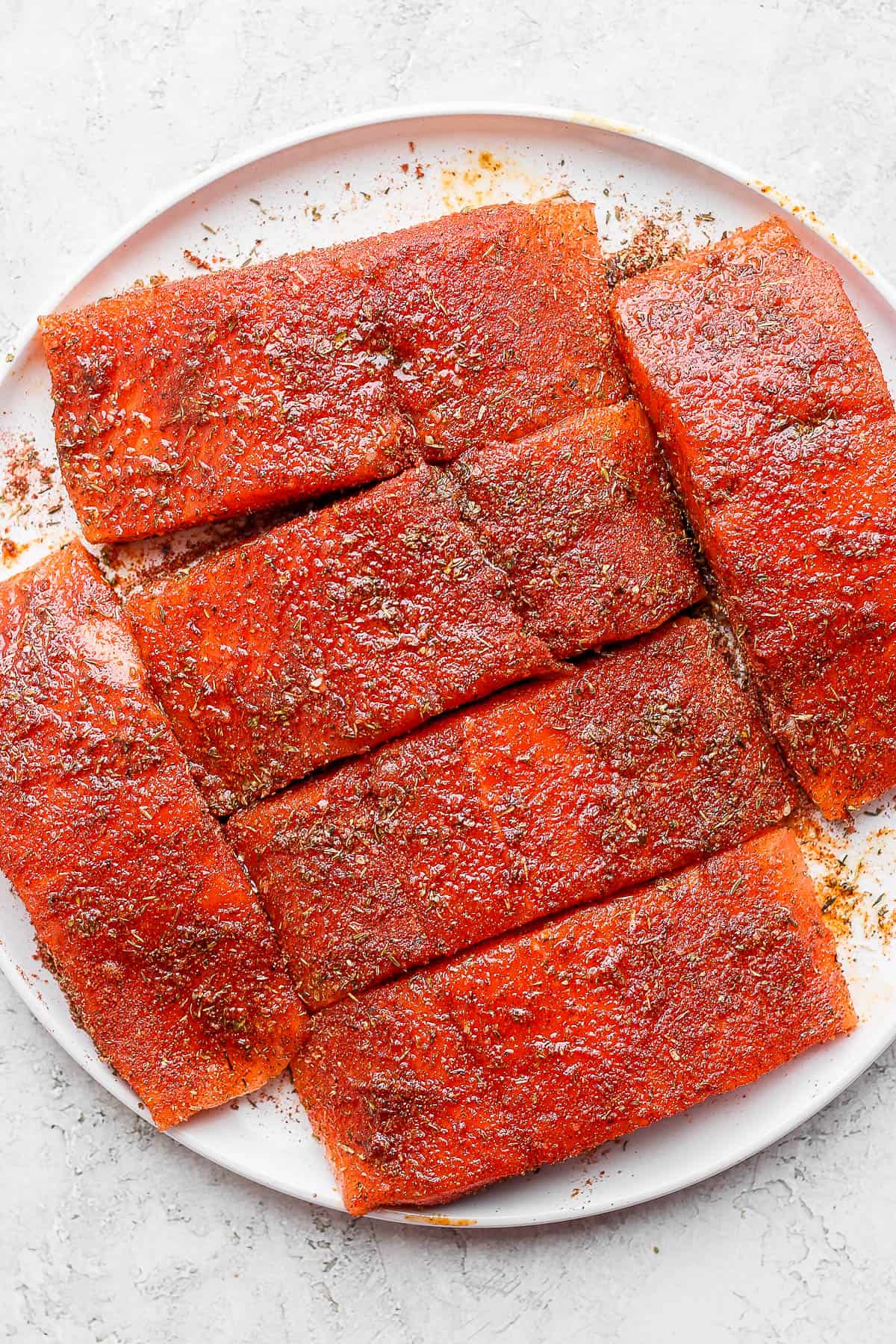 Salmon fillets covered in seasoning and olive oil.