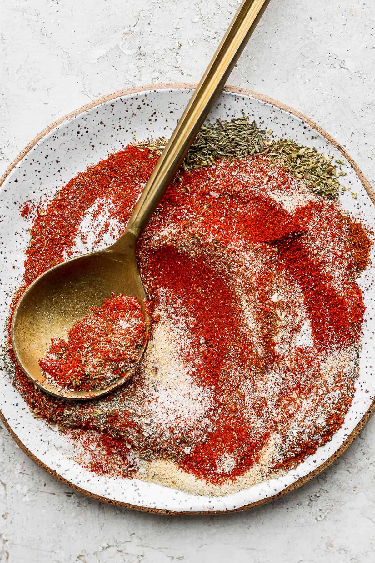 Plate of blackened seasoning mixed together with gold spoon.