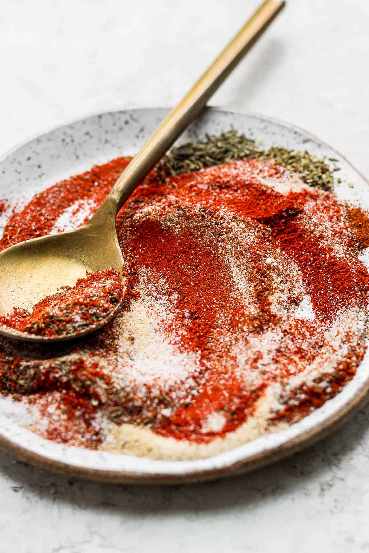 Plate of blackened seasoning with gold spoon.