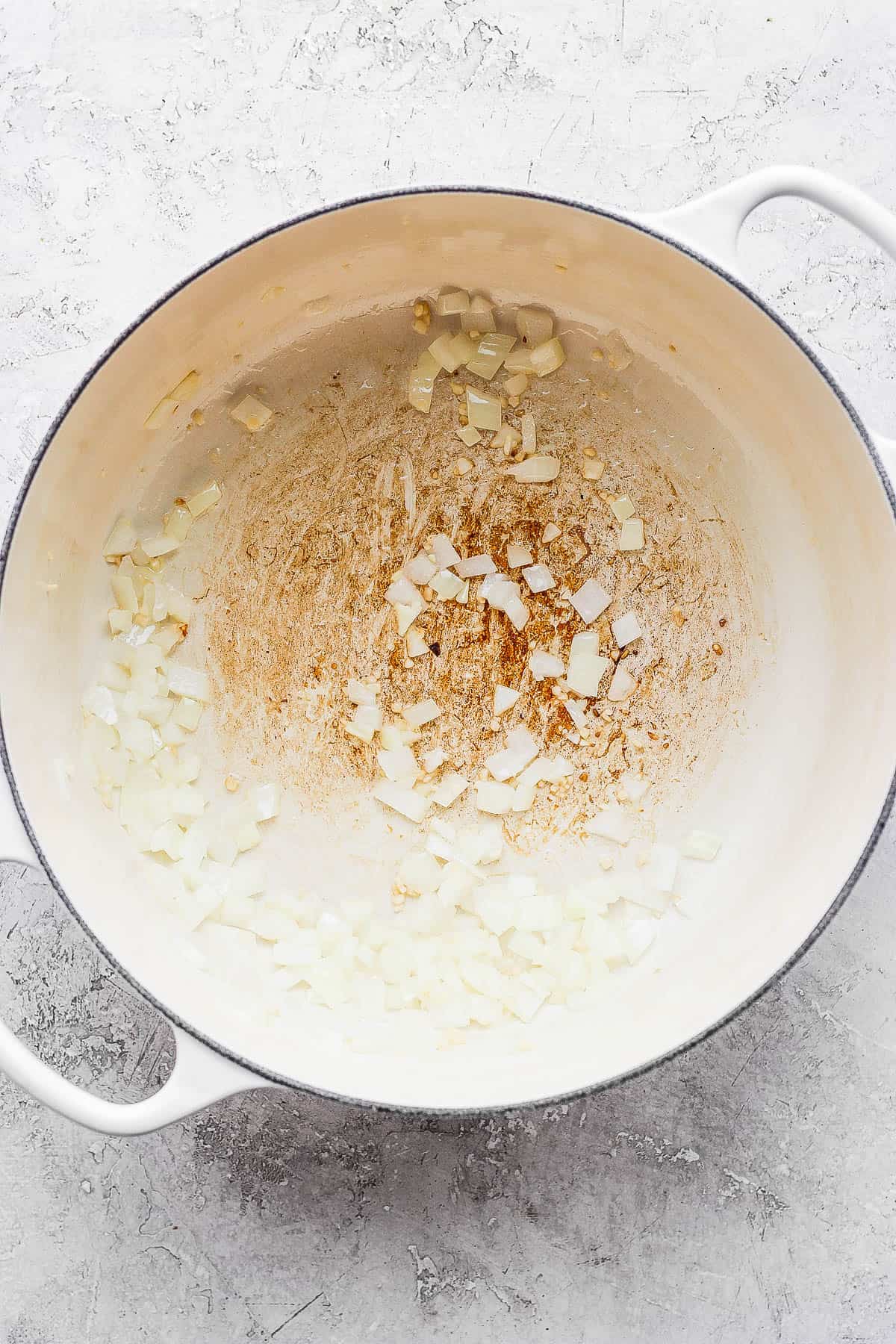 Onions and garlic being sauteed in a dutch oven.