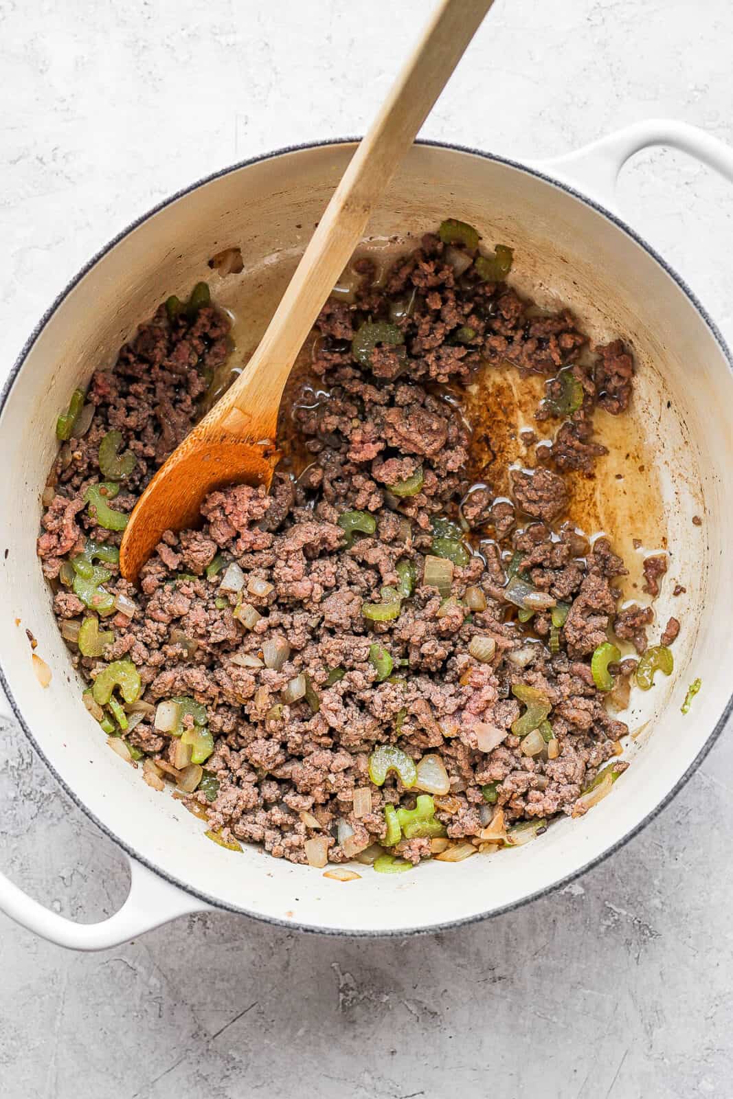 Ground beef and celery cooked in a dutch oven.