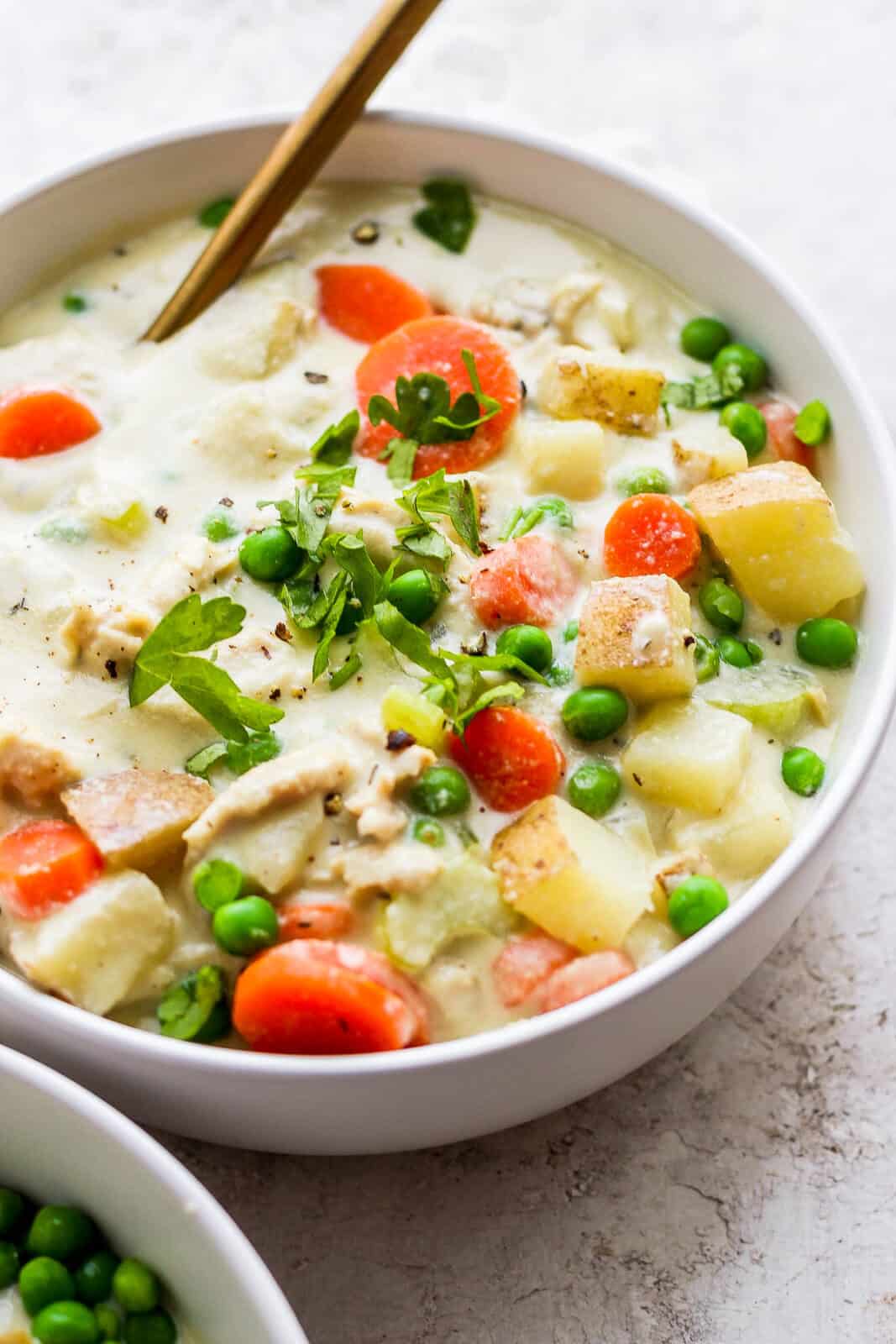 A bowl of chicken pot pie soup with a spoon.