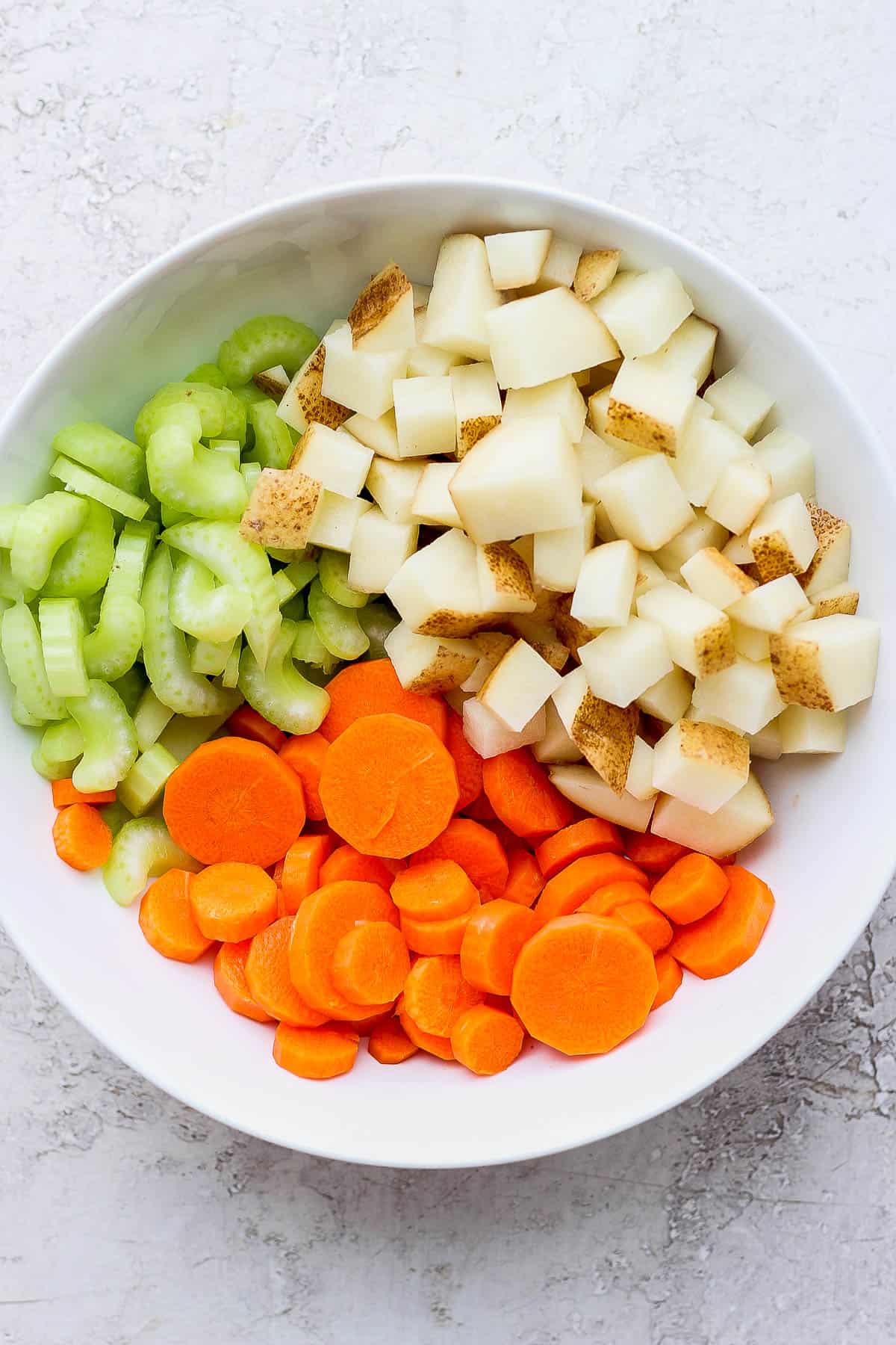Cut-up celery, carrots, and potatoes in a bowl.