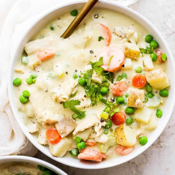 A bowl of chicken pot pie soup with a gold spoon sticking out.