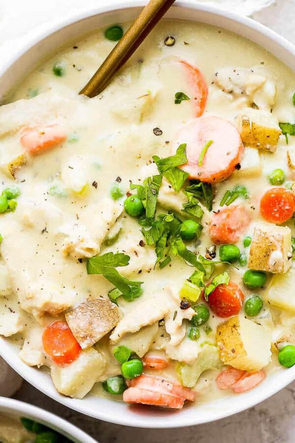 A bowl of chicken pot pie soup with a gold spoon sticking out.
