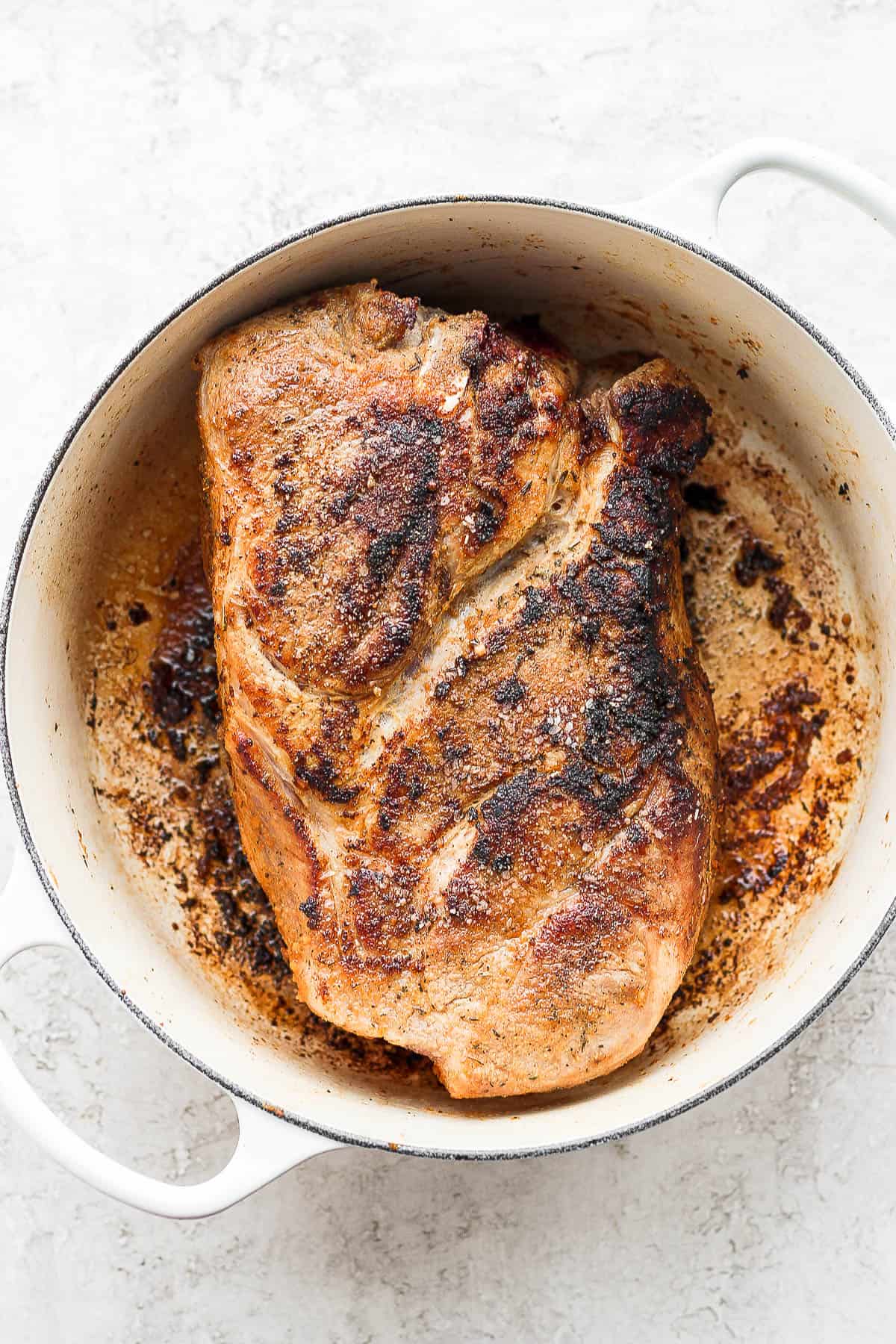 A roast seared on all sides in a dutch oven. 