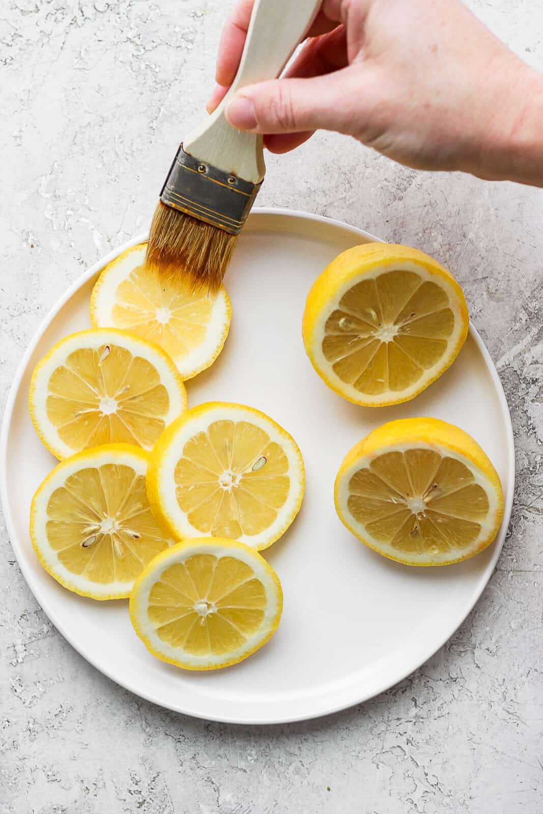 Brushing olive oil on lemon slices.