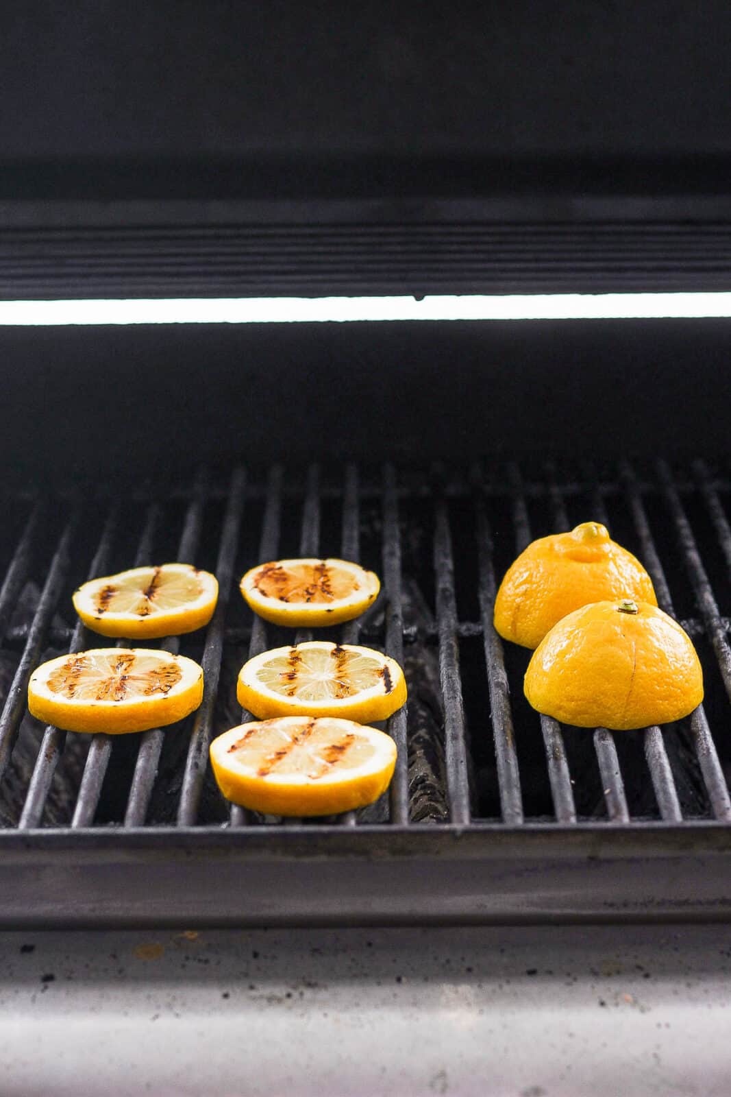 Lemon slices and lemon halves on a grill.