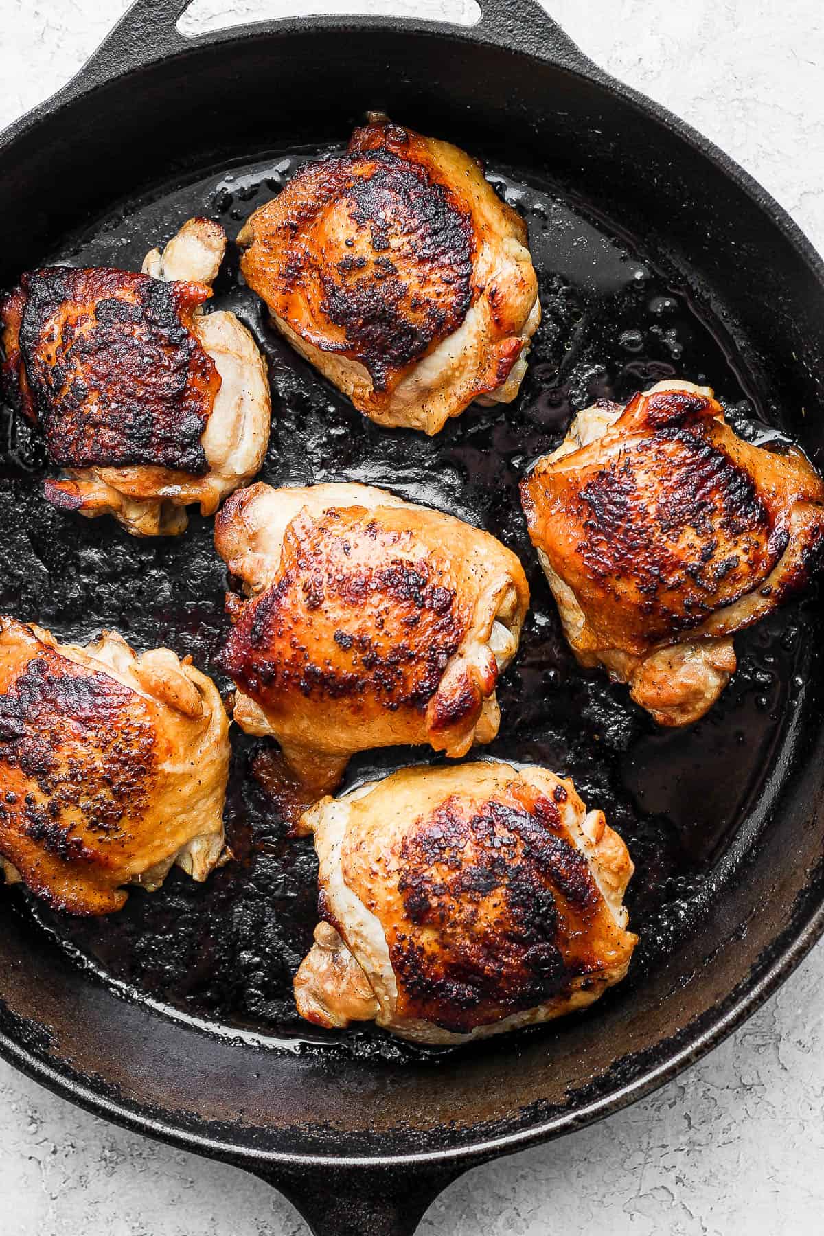 6 chicken thighs fully cooked in a cast iron skillet.