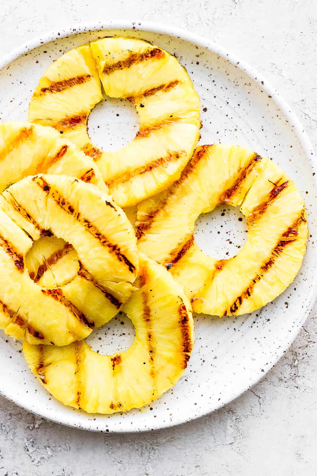 Grilled pineapple slices on a plate.