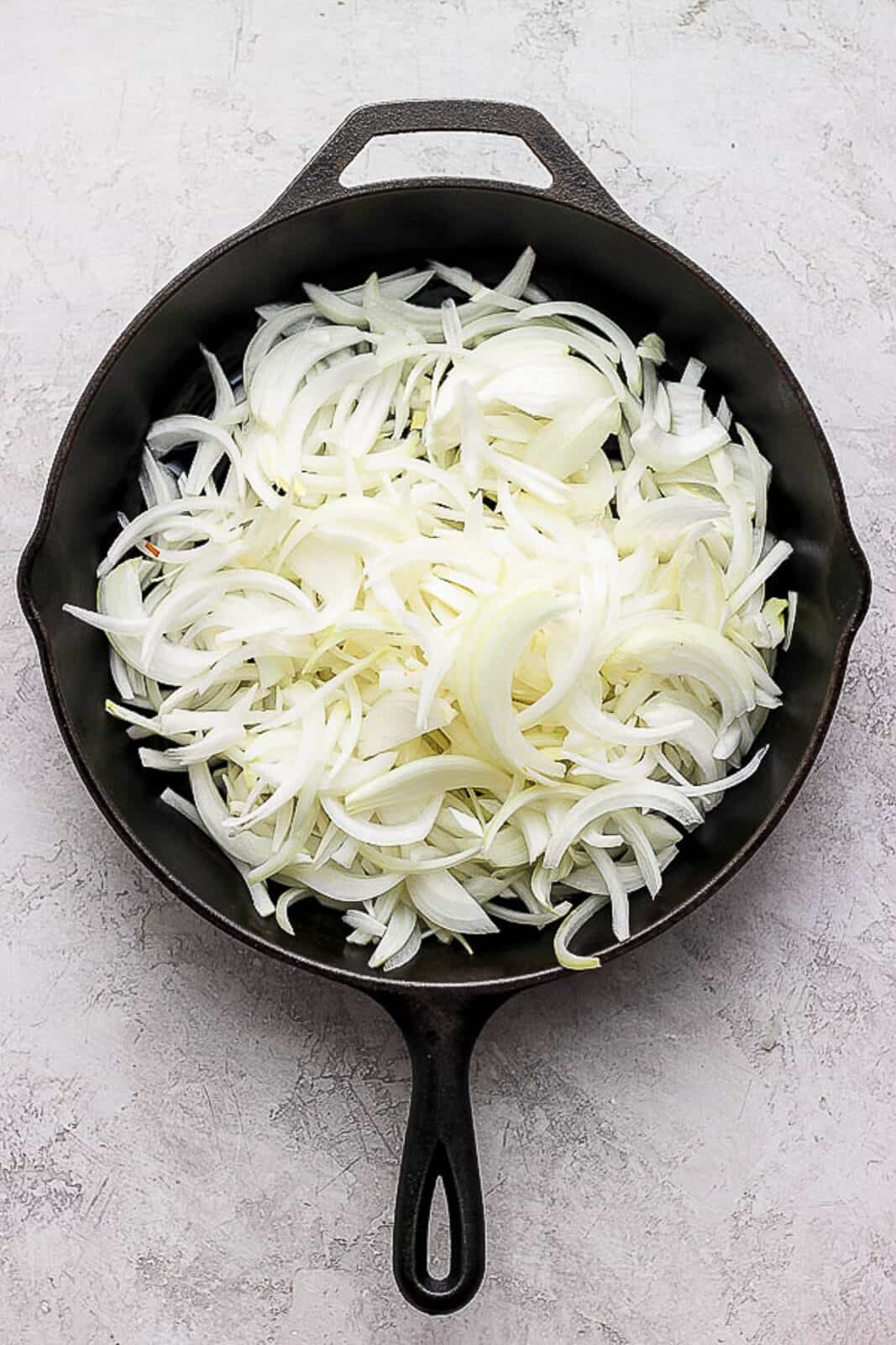 Raw onion slices in a cast iron skillet.