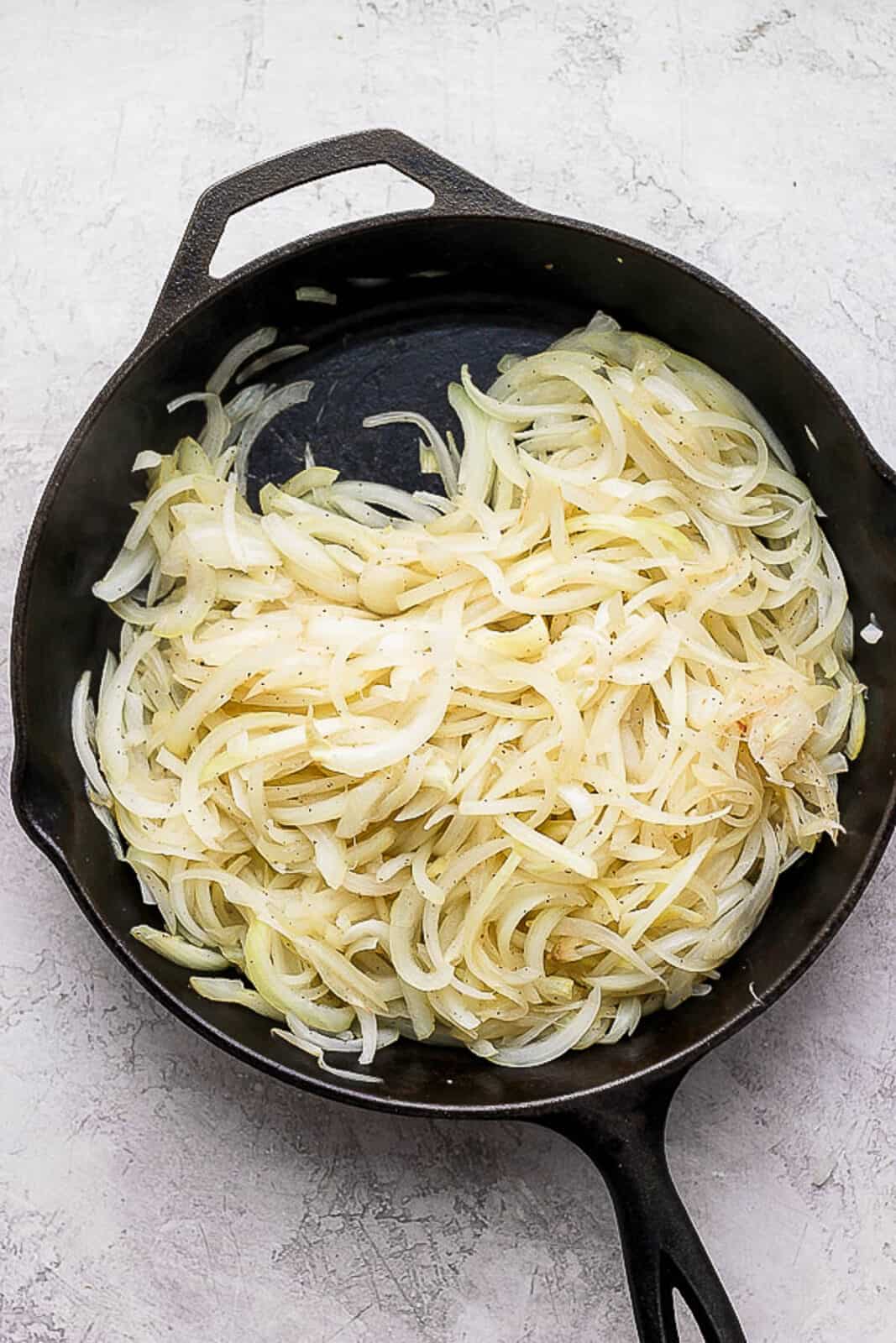 Onions beginning to caramelize in a skillet.