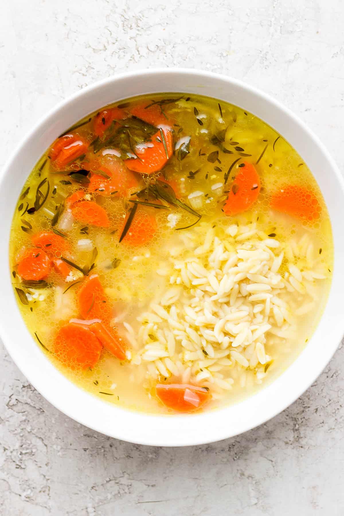 Bowl of soup over cooked orzo.