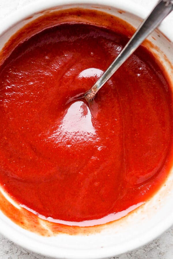 Bowl of homemade meatloaf glaze with spoon sticking out.