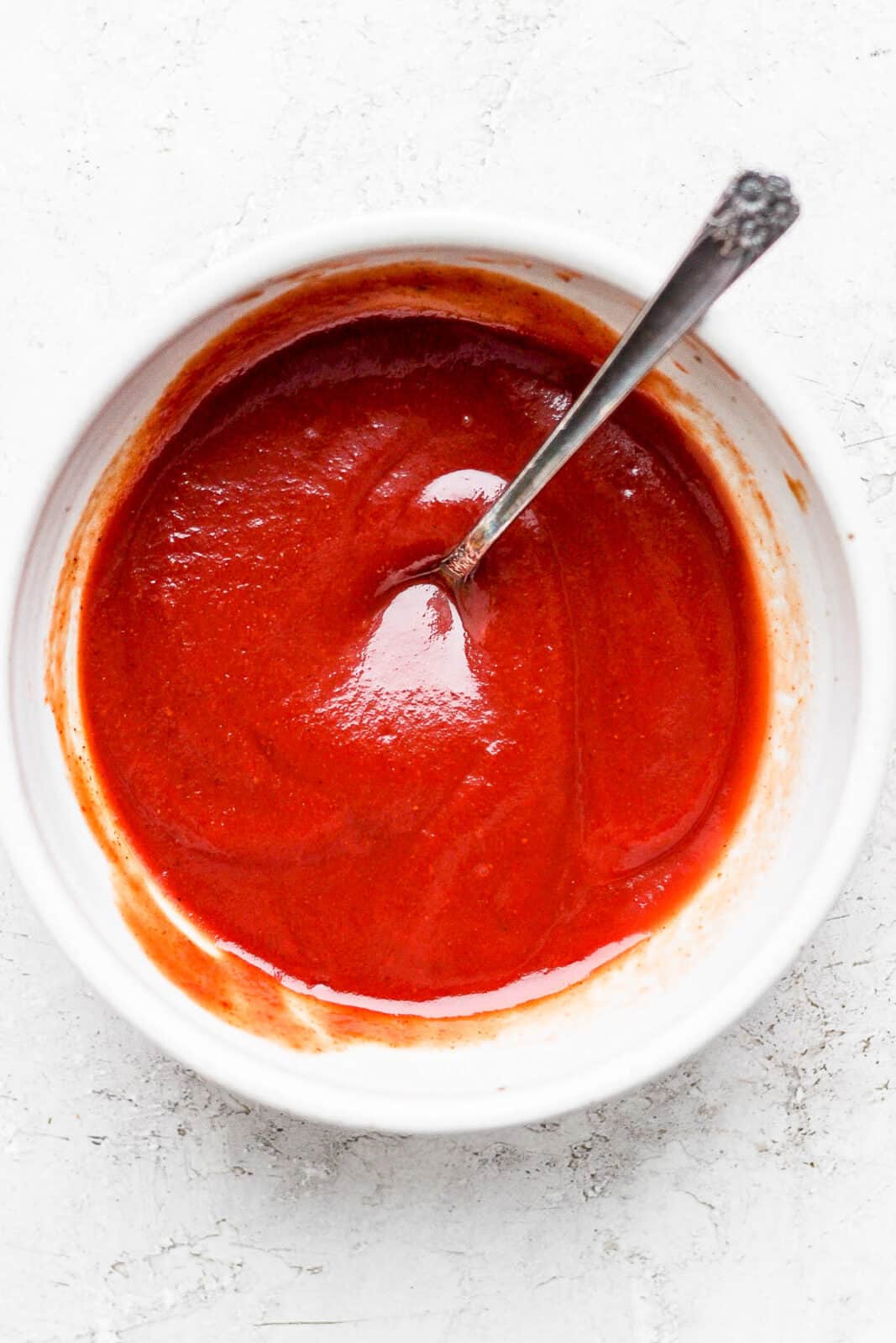 Bowl of meatloaf glaze with spoon sticking out.