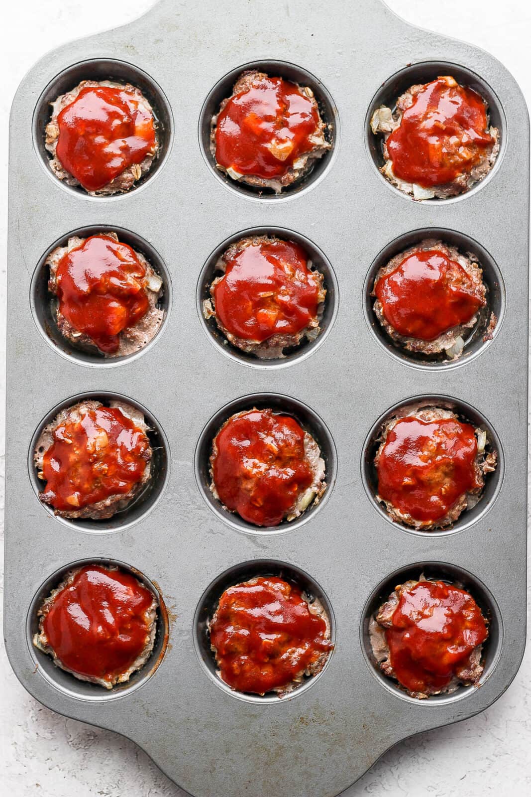 Mini meatloaves in muffin tin with glaze on top. 