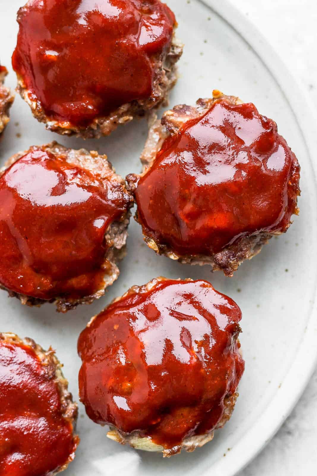 Mini meatloaf on a plate with glaze on top. 