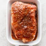 A pork roast in a baking pan covered in pork roast marinade.