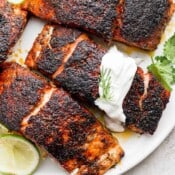 A plate of salmon with a dollop of salmon dill sauce on top.