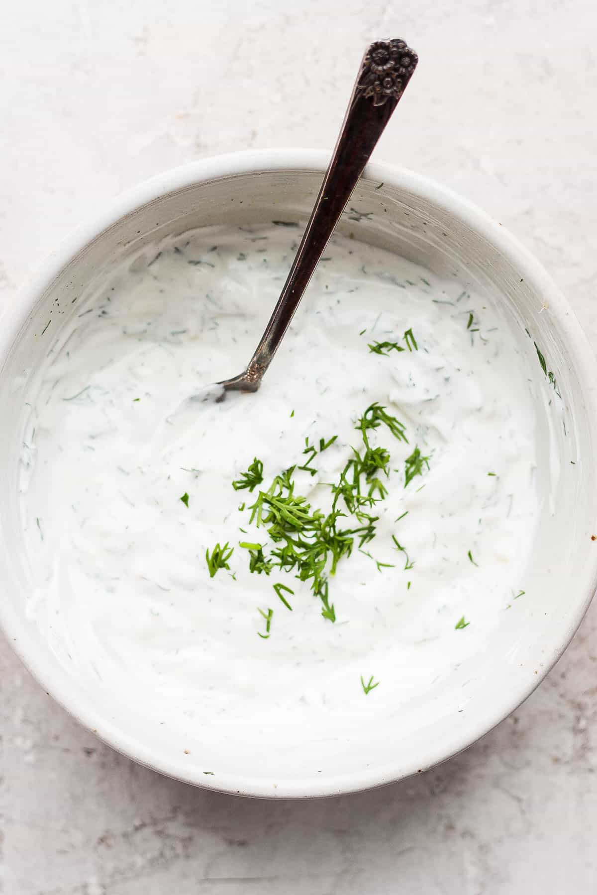 A small bowl of dill sauce with a spoon.