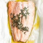 Salmon en papillote on a piece of parchment with fresh thyme.