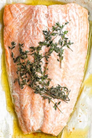 Salmon en papillote on a piece of parchment with fresh thyme.