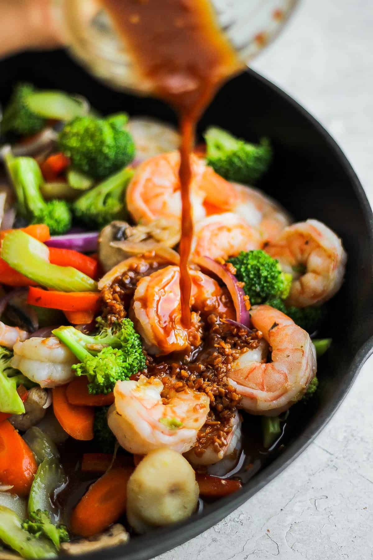 Stir fry sauce being poured over the shrimp stir fry.