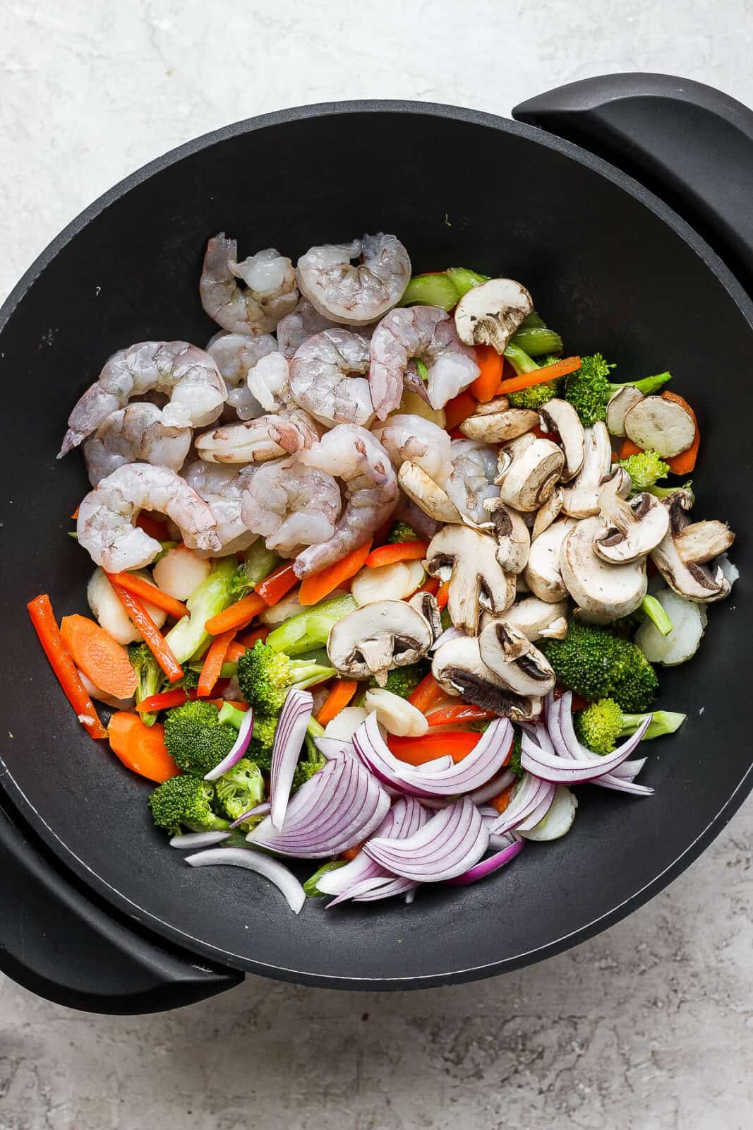 The wok with shrimp, red onion, and mushrooms added.