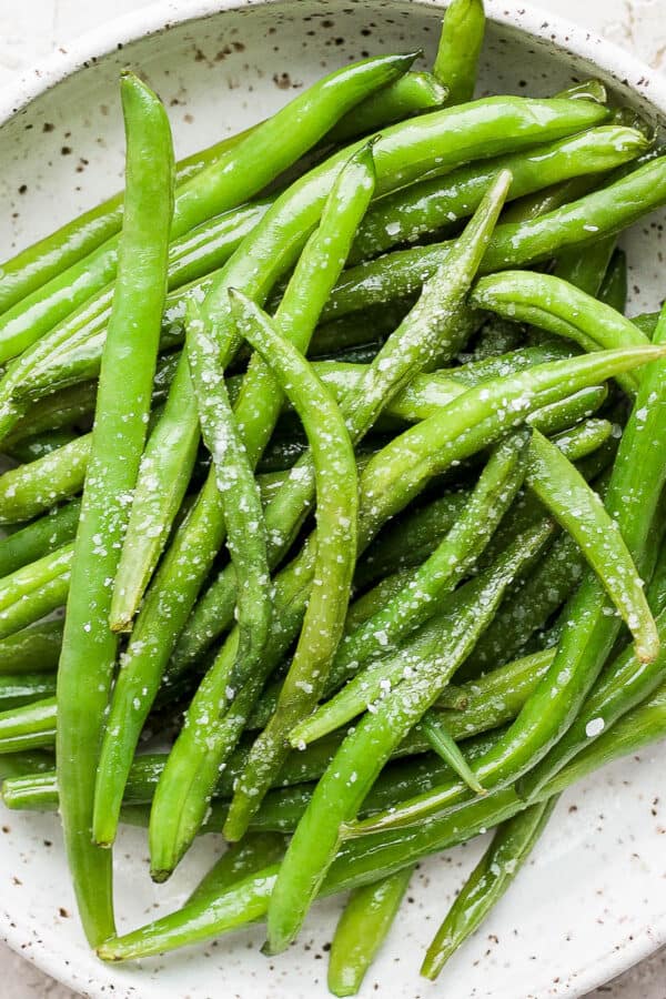 Smoked green beans in a shallow dish with some salt sprinkled on top.