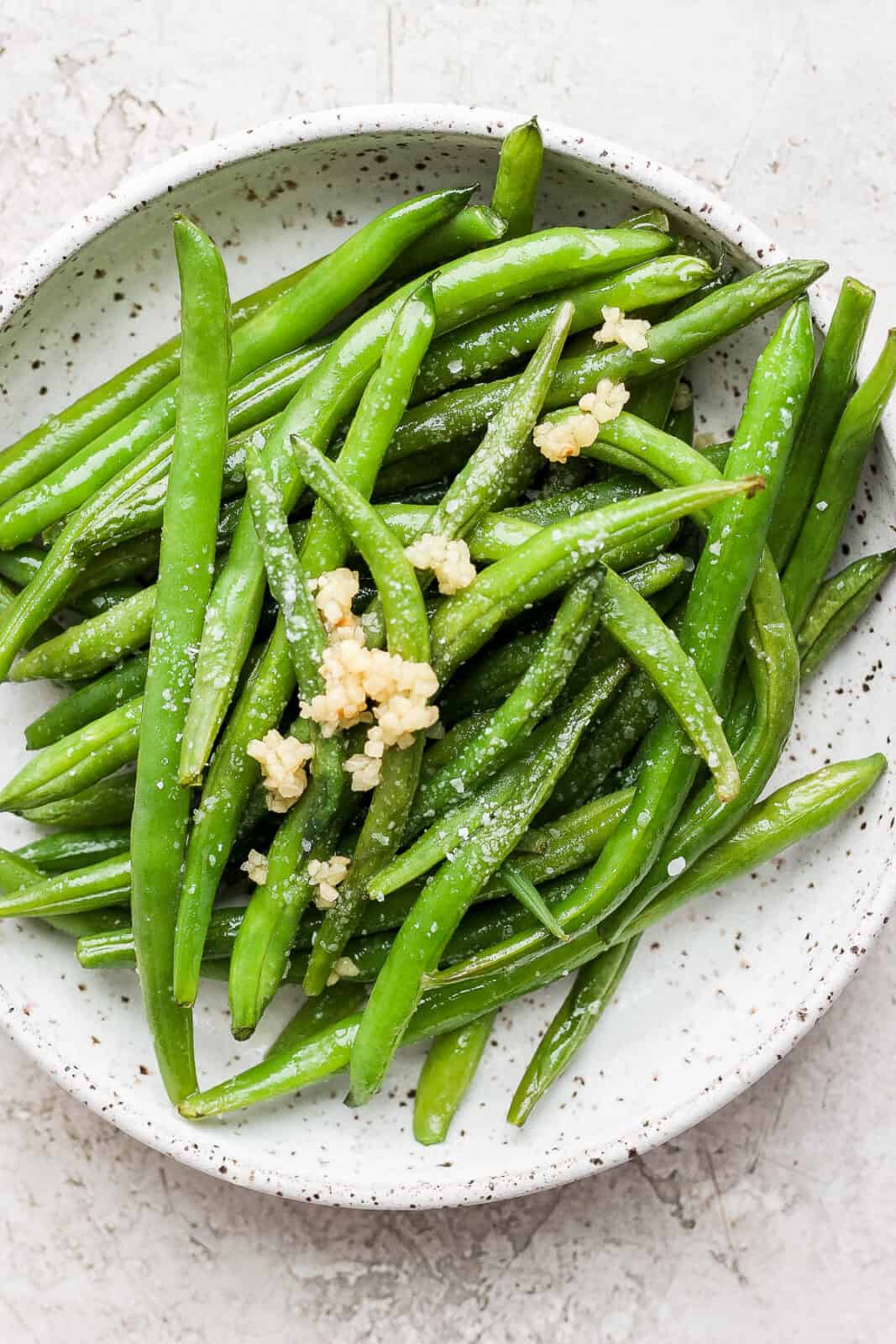 Bowl of smoked green beans with garlic on top. 