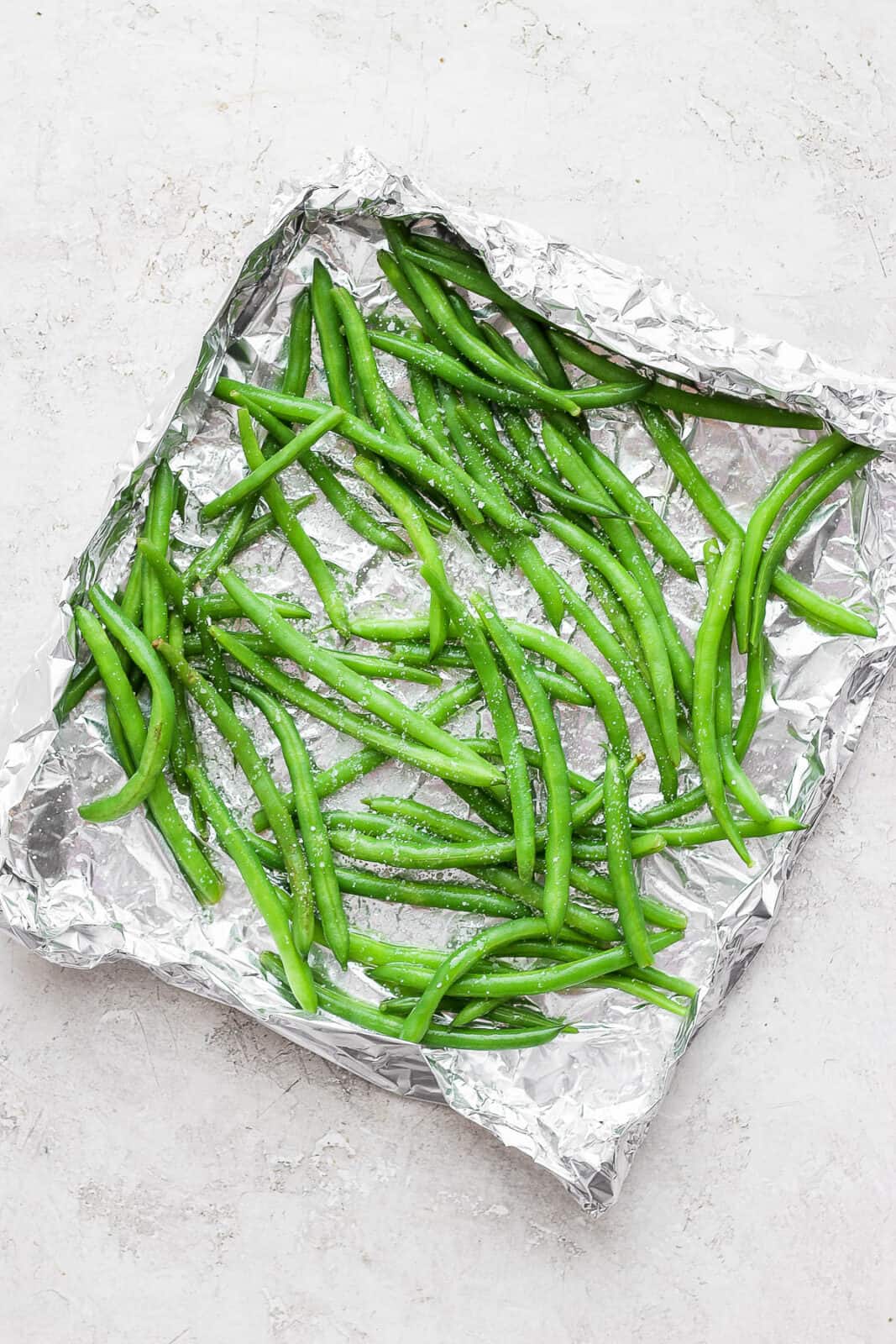 Green beans in a foil basket with salt and olive oil. 