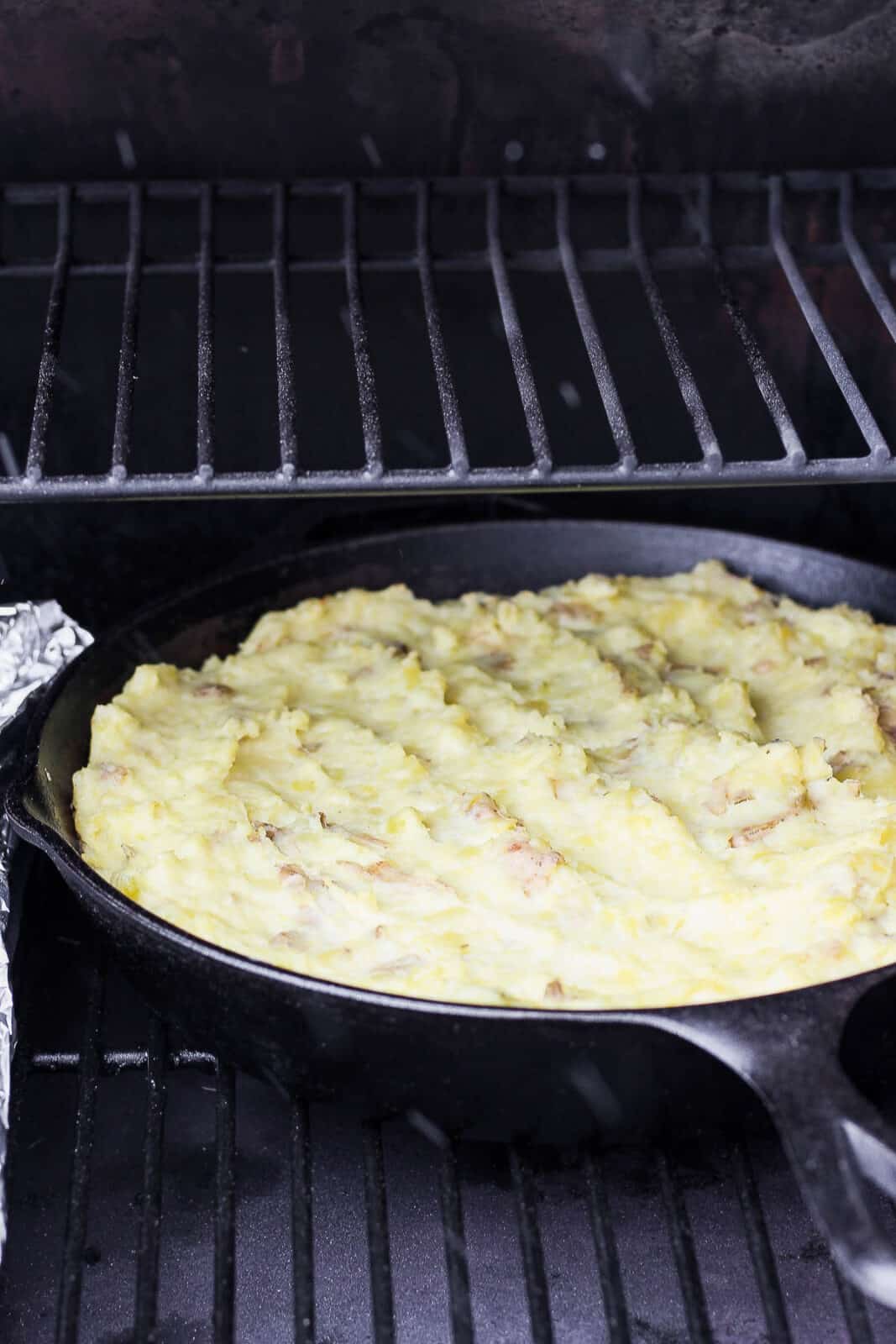 Mashed potatoes in a cast iron skillet on the smoker. 