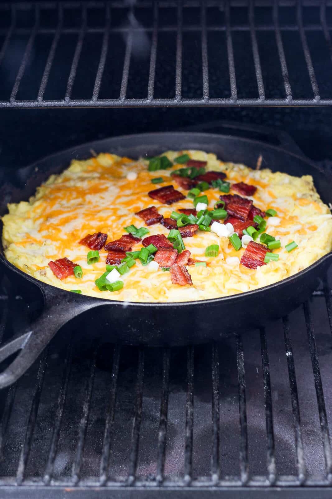 Smoked mashed potatoes on a smoker while cheese melts.