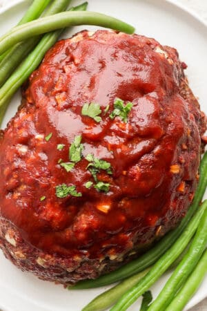 Smoked meatloaf on a plate with green beans.