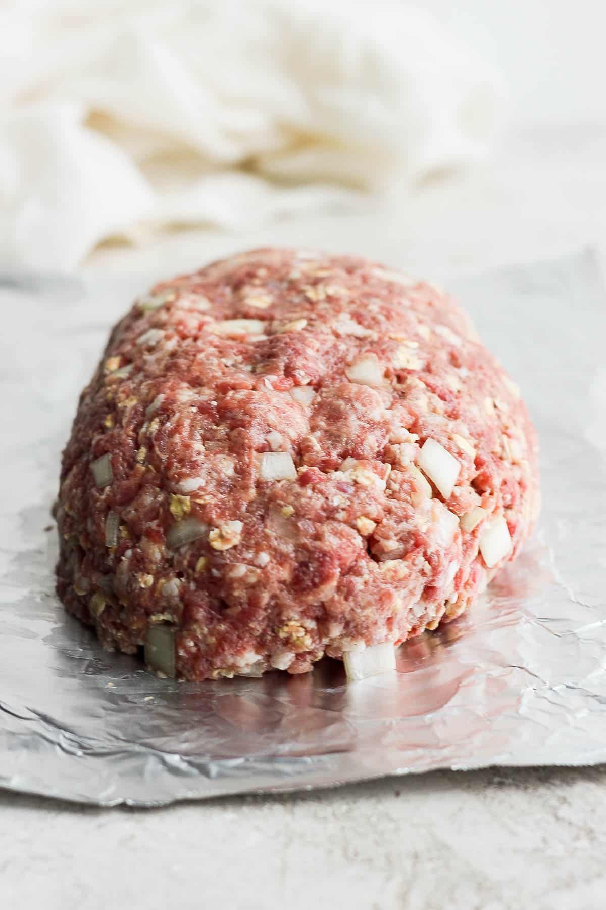 Meatloaf mixture formed into a loaf on a piece of foil.