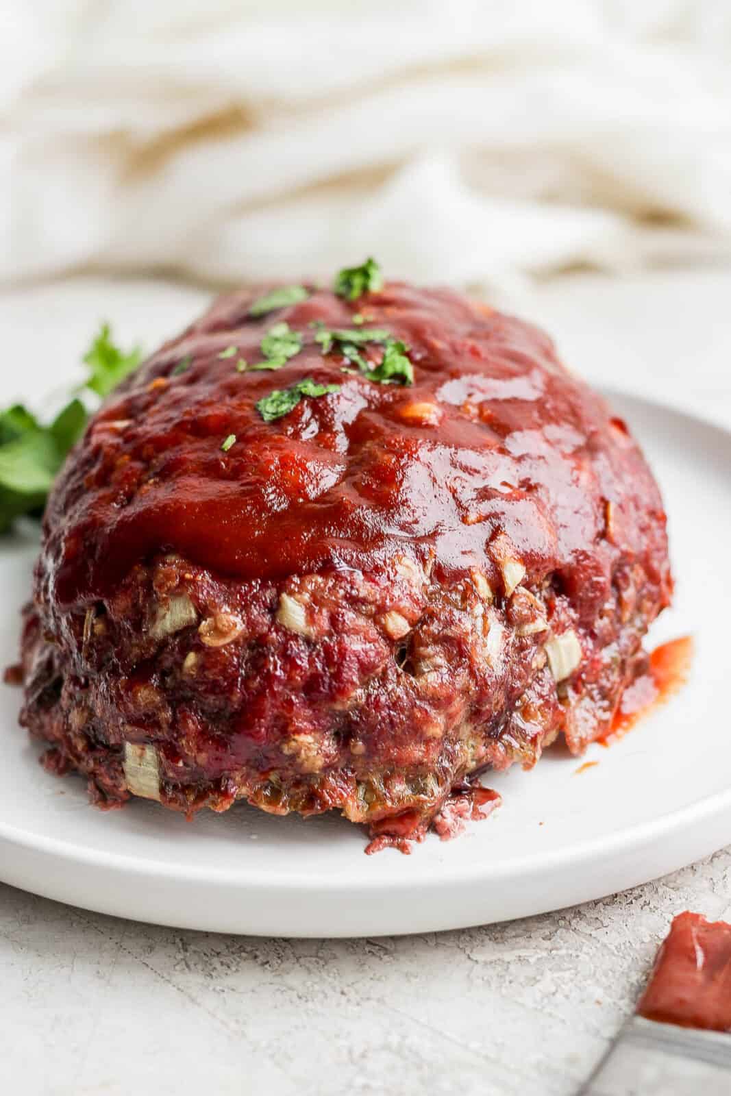 Smoked meatloaf on a plate and garnished with shopped parsley.