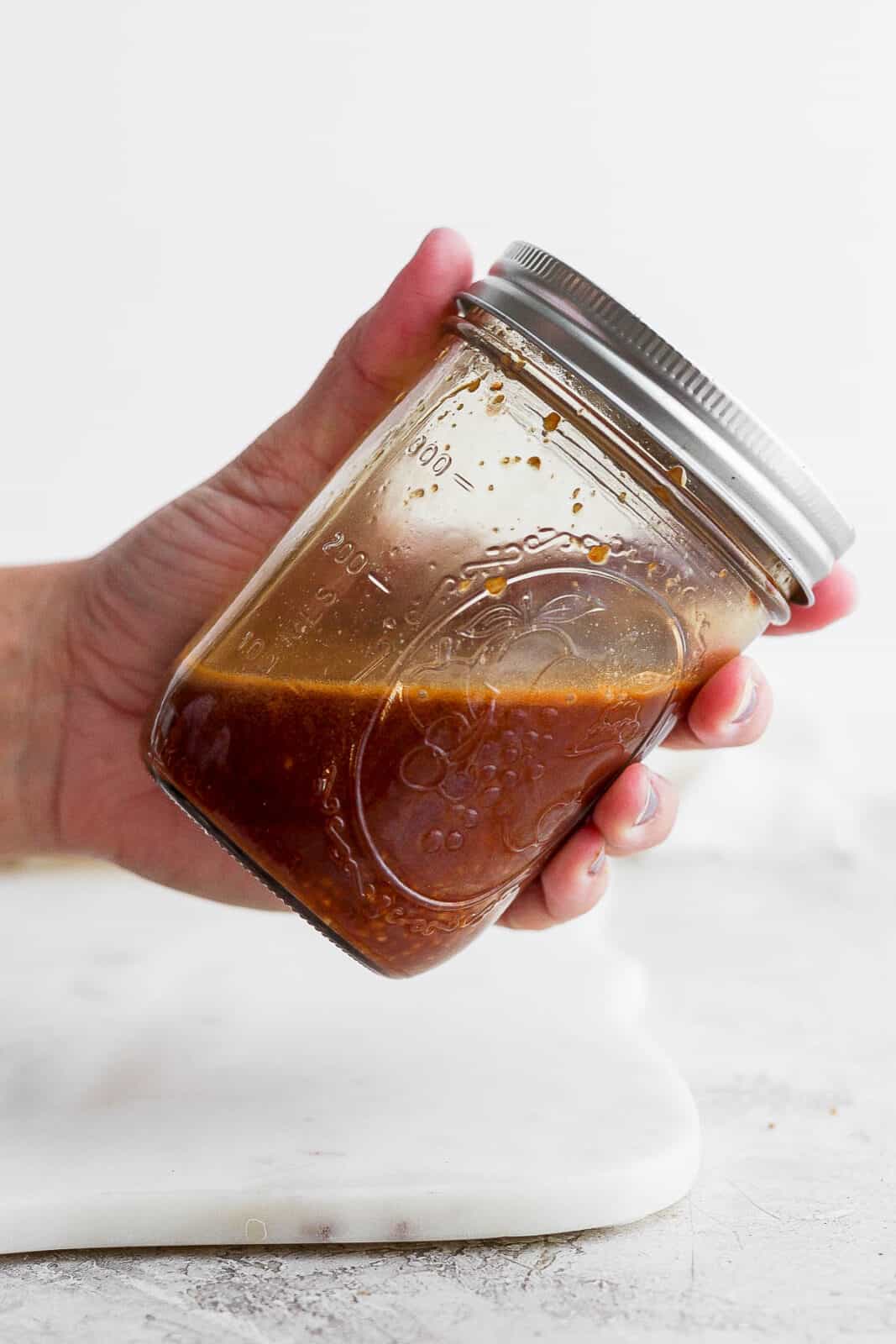 A mason jar of stir fry sauce being shaken.