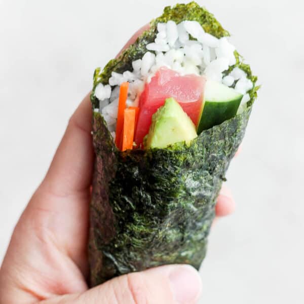 Someone holding a sushi hand roll.